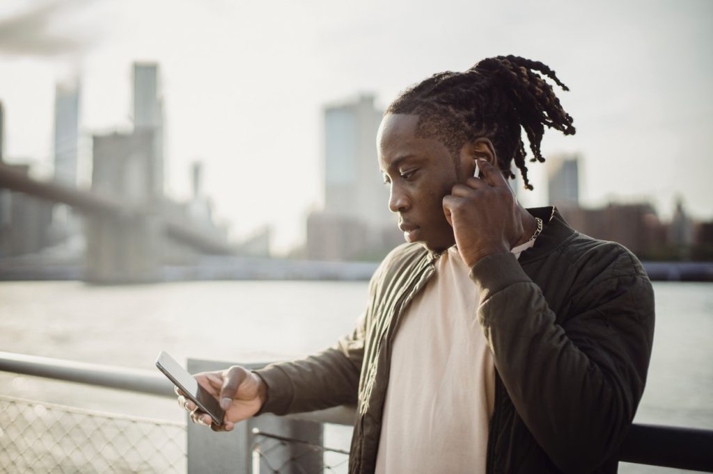 A man standing near a bridge completes an online purchase on his phone.