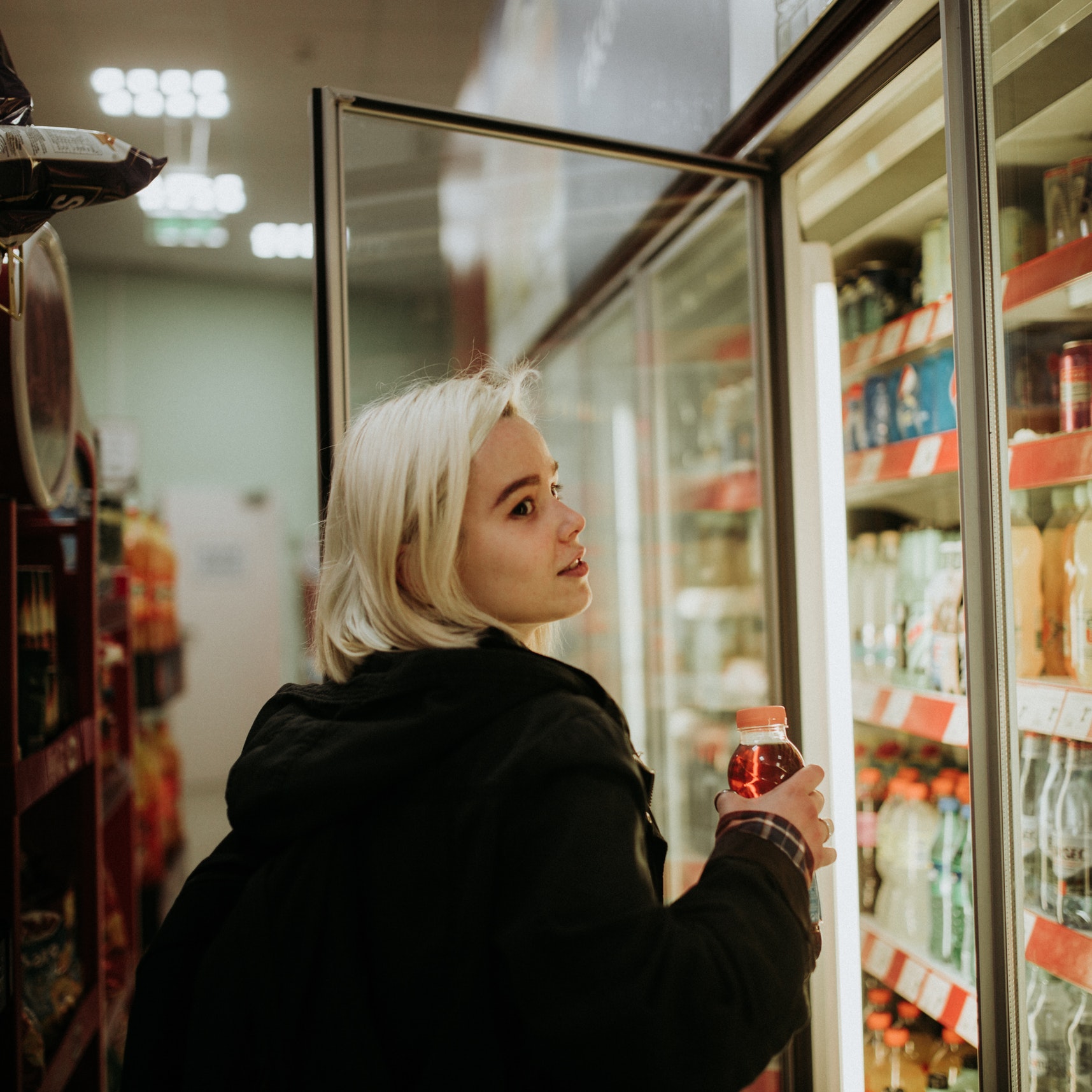 A woman buys a drink at a gas station store