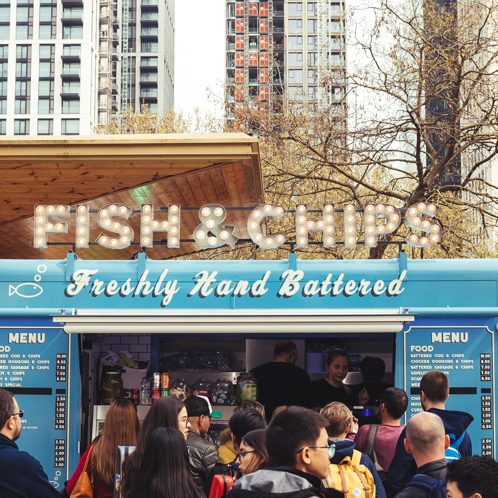 A food truck parked in front of tall apartment buildings