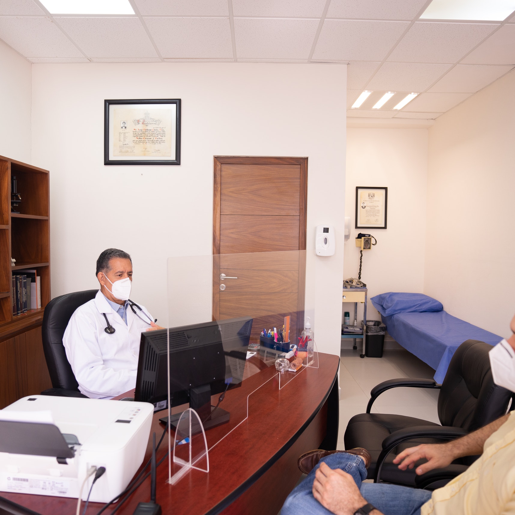 A doctor consults with a patient from behind a desk