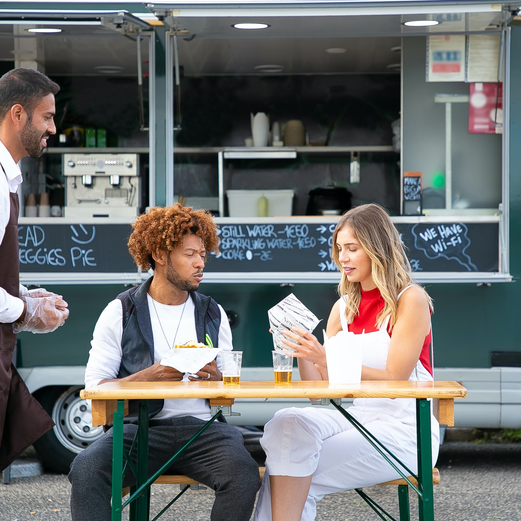 Two friends eating at a table in front of a food truck