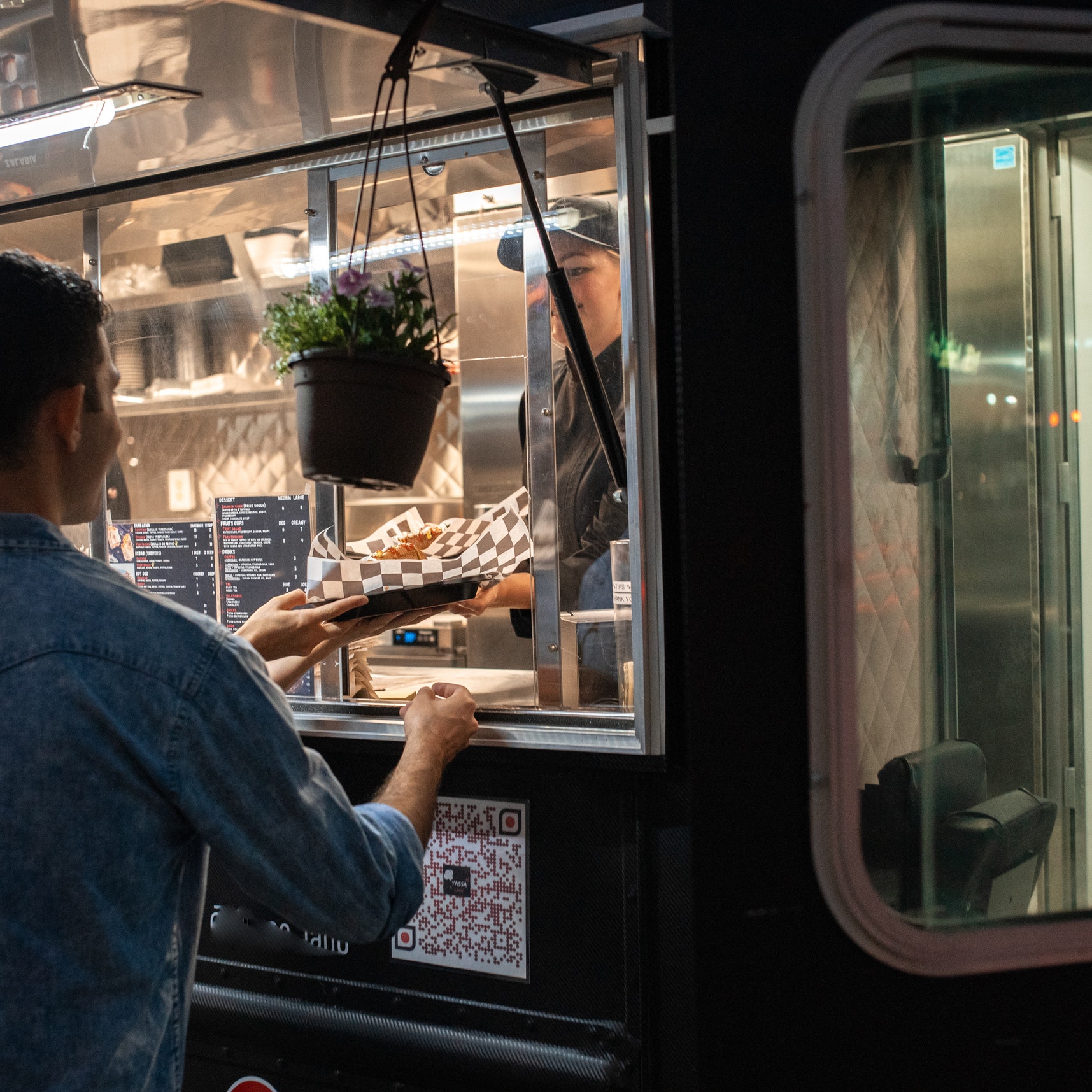 A man receives an order from a food truck window