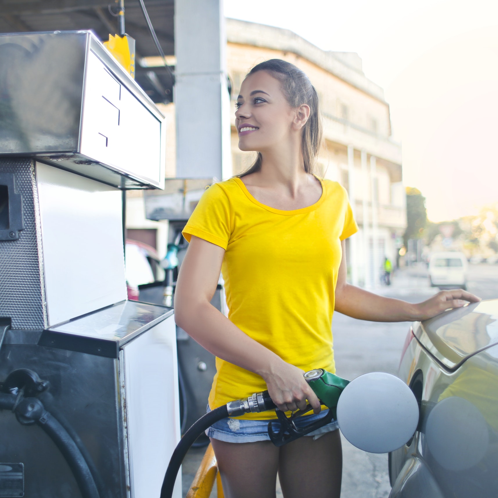 A woman fuels her car at a gas station