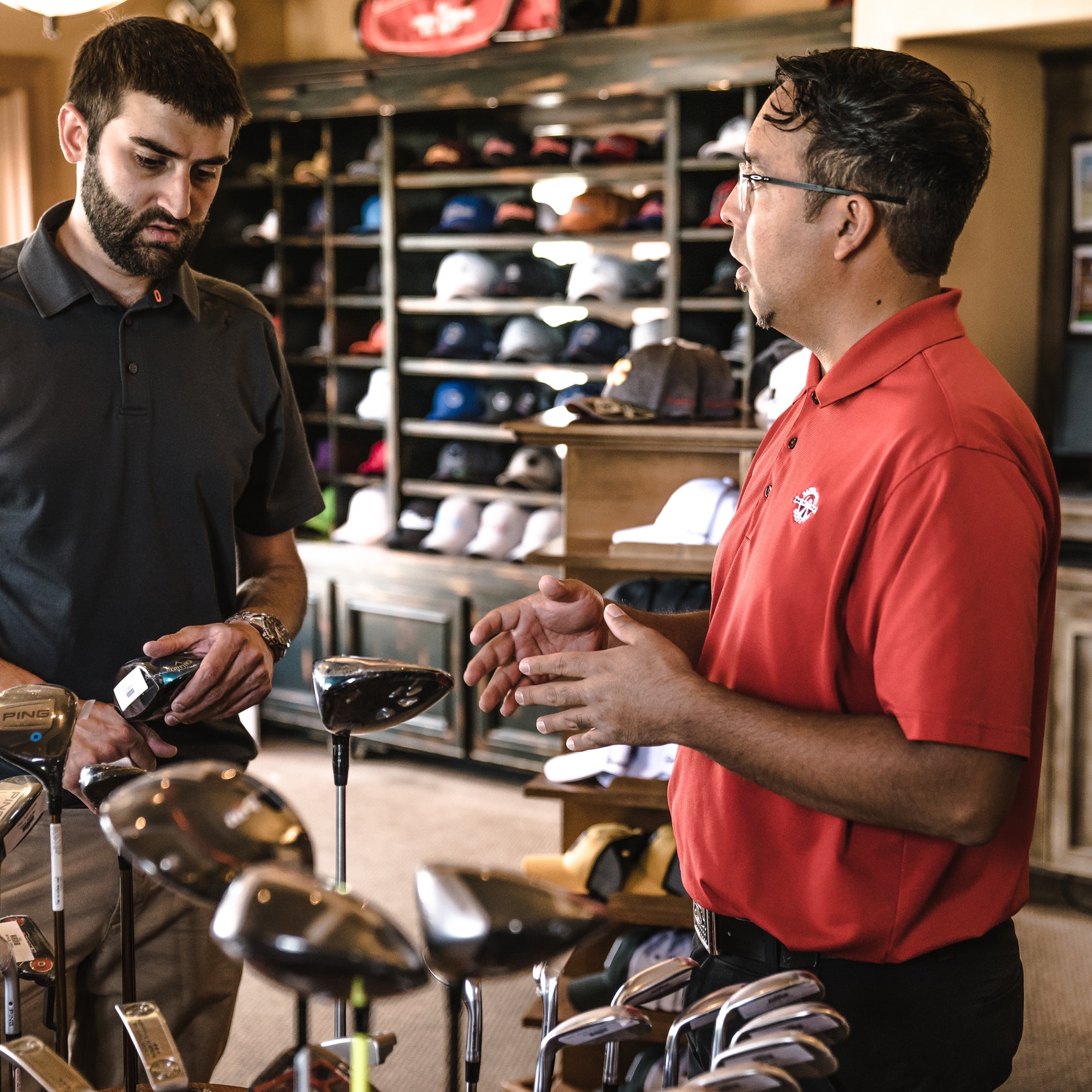 A salesperson showing a customer different golf clubs in a sporting goods store