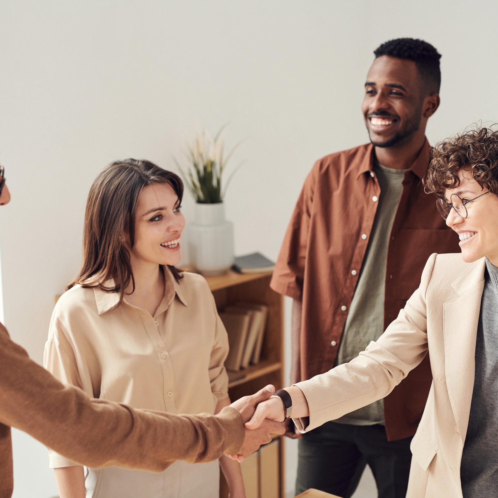 A group of smiling people shake hands after a business deal