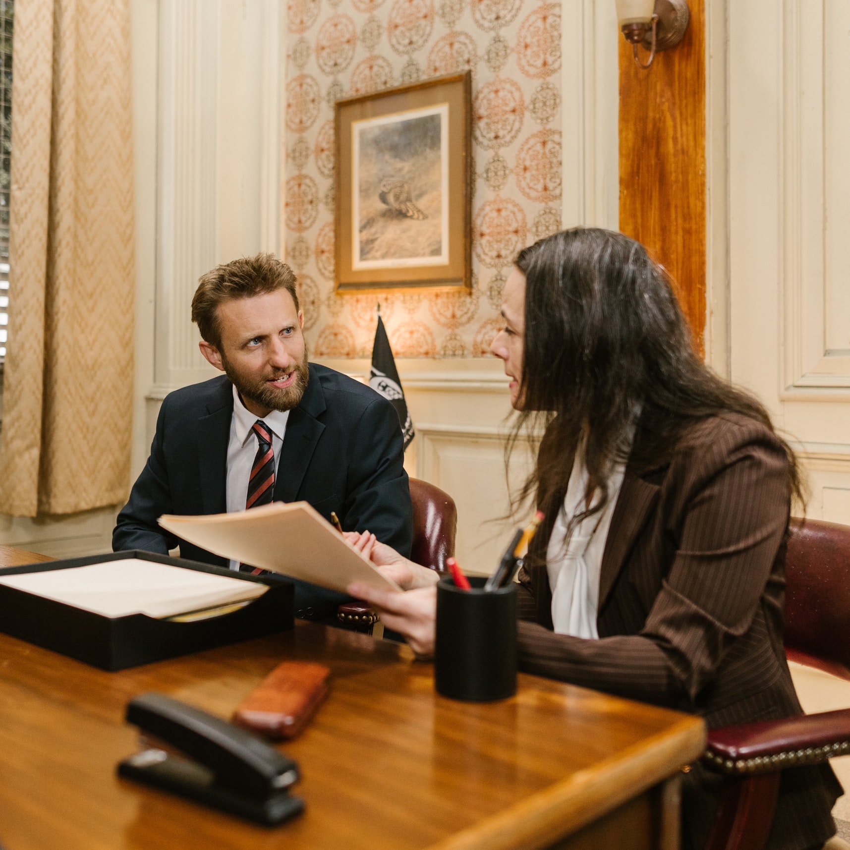 A man and woman have a discussion at a law office desk