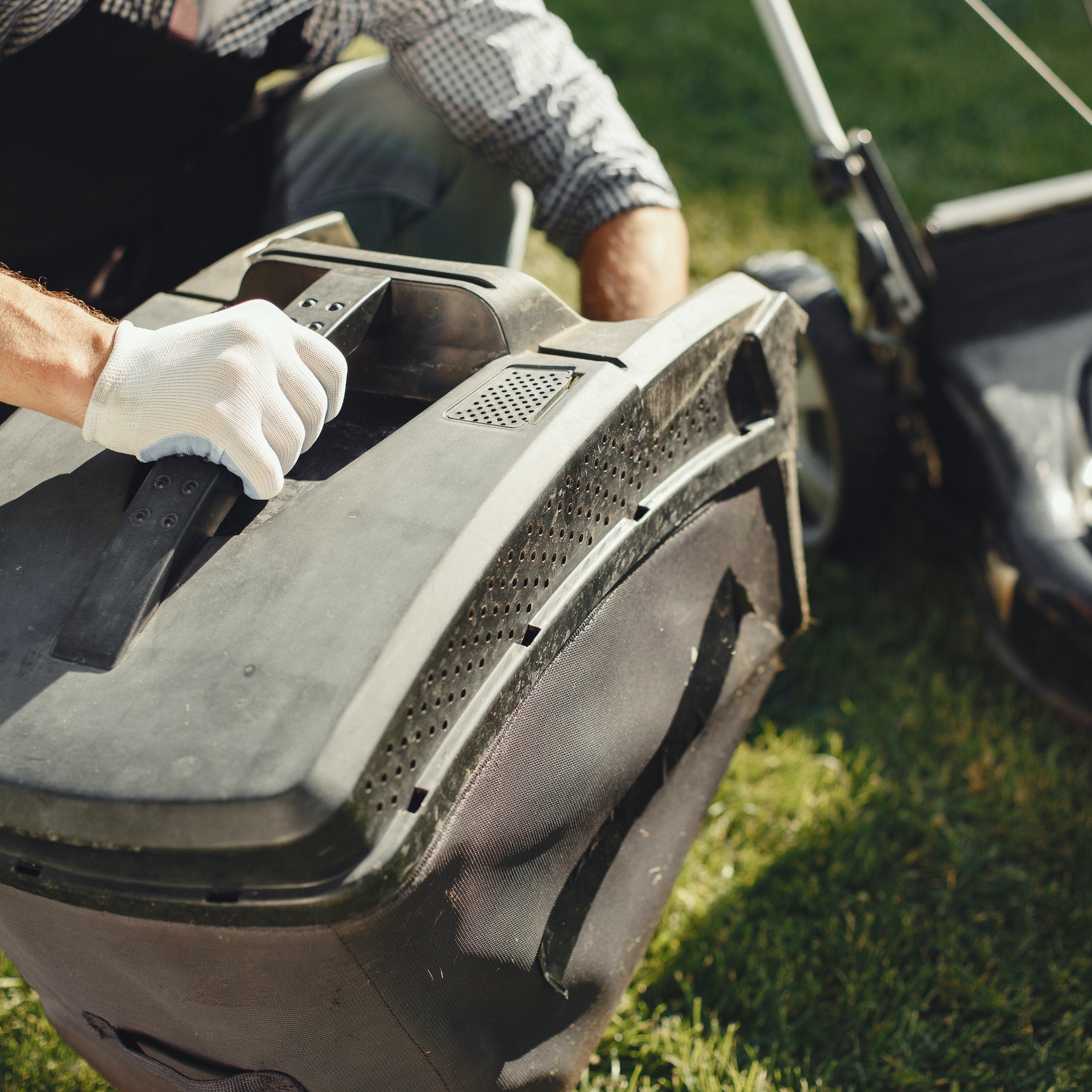 A man inspects a lawnmower before repairing it