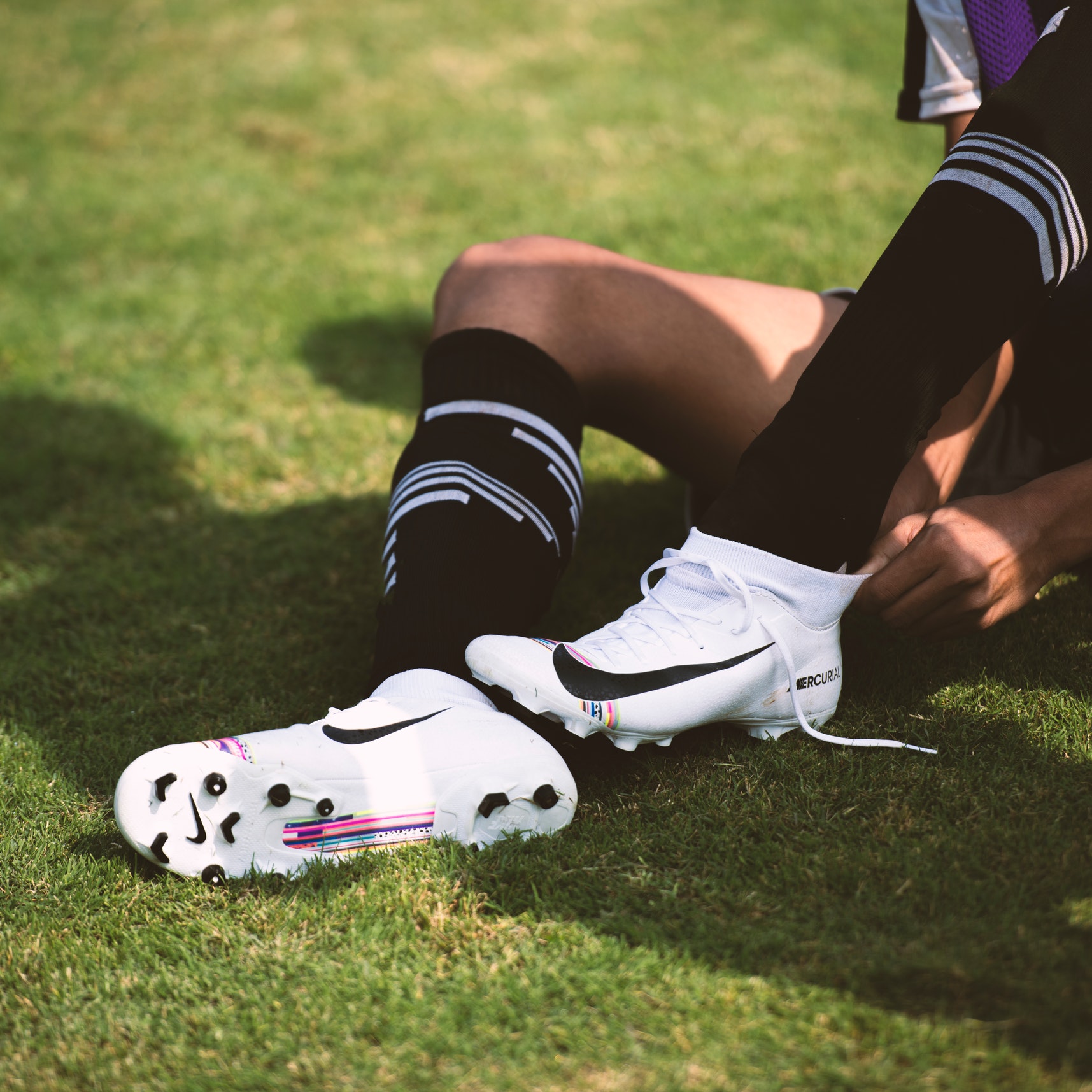 A soccer player puts on cleats