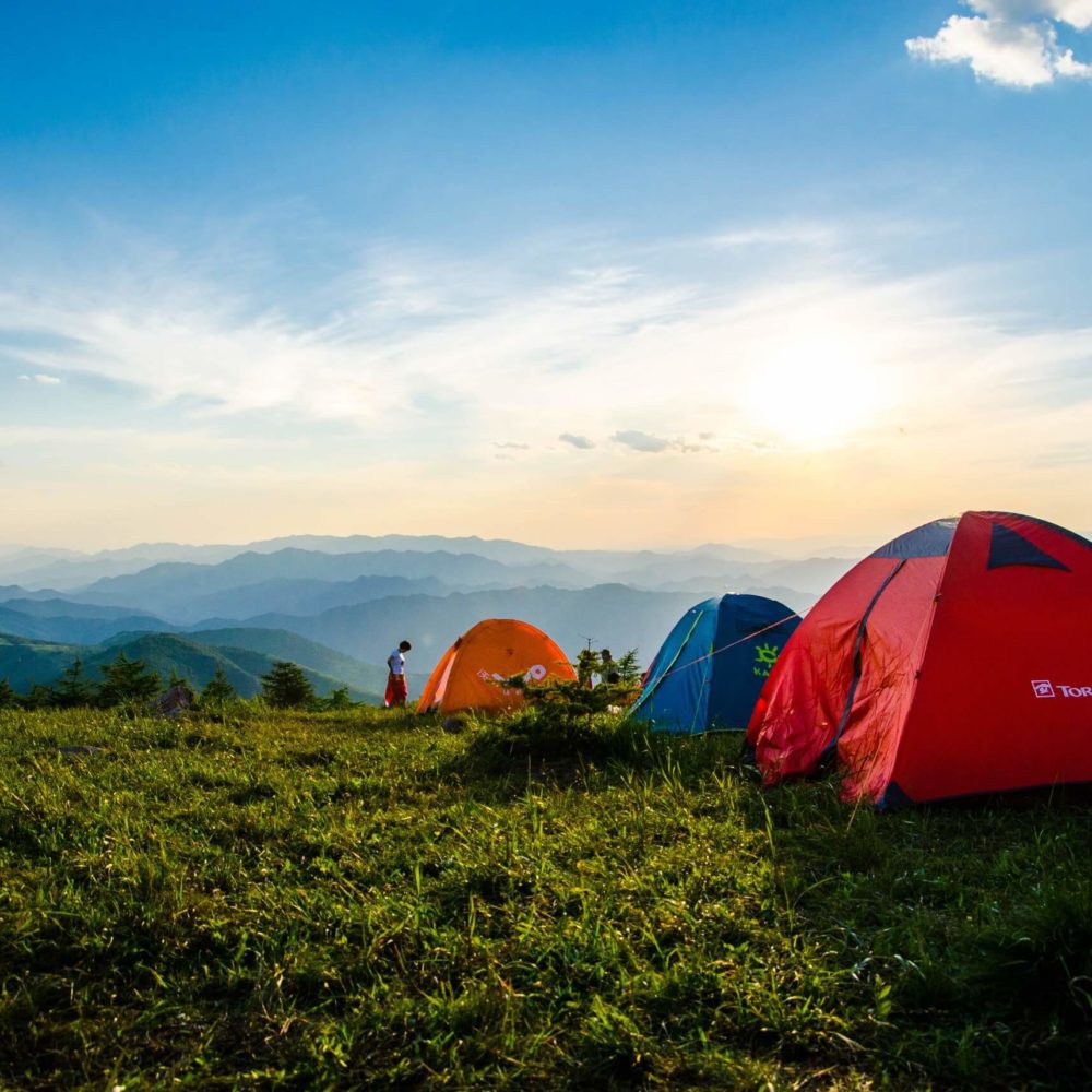 Multiple Tents on a green mountaintop