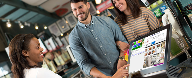 A restaurant worker takes the order of two customers on a point-of-sale system