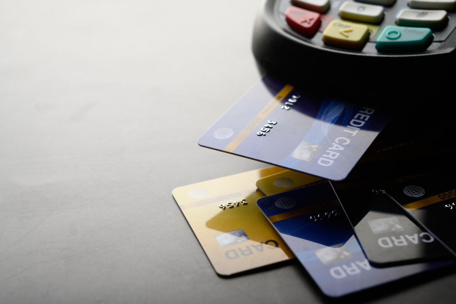 A pile of credit cards next to a credit card terminal